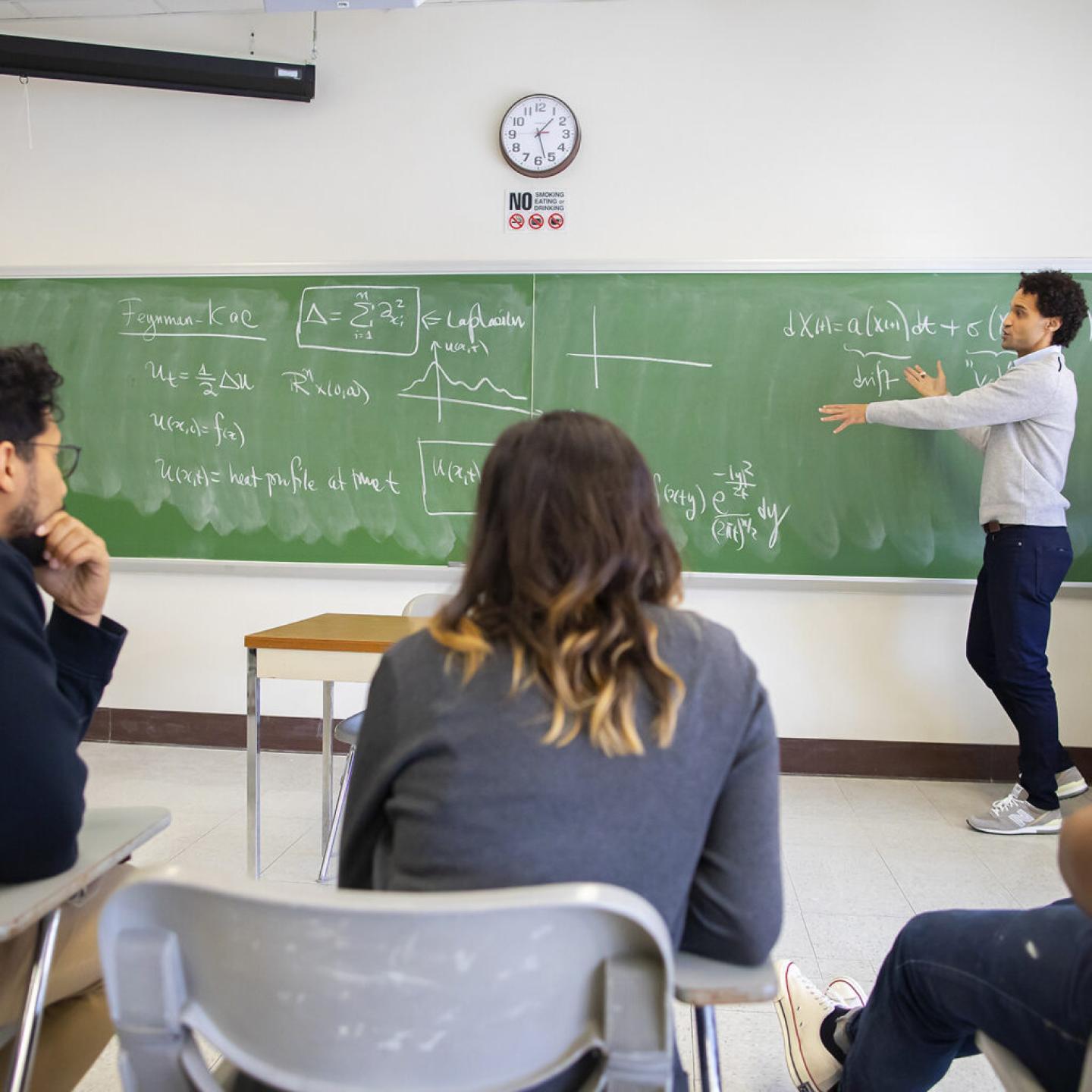 Instructor explaining equations to class at blackboard