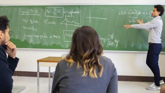 Instructor explaining equations to class at blackboard